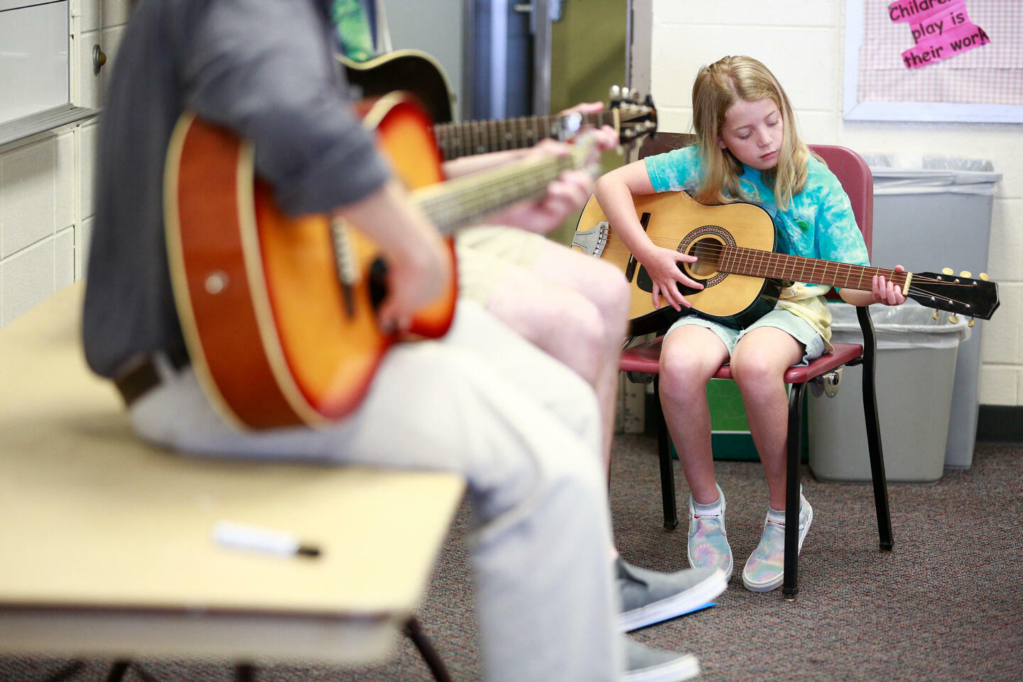 student teaching child how to play guitar